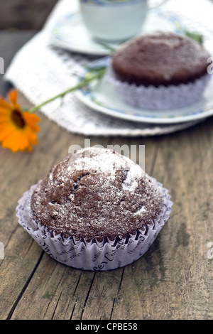 Muffin mit einem Cappuccino auf einer alten hölzernen Board und Ringelblume-Blume Stockfoto