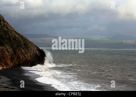 Wellen, die gegen die Klippe unten Criccieth Schloß Lleyn Halbinsel Gwynedd Wales Stockfoto