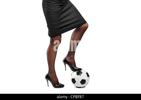 Frau in Highheels, stehend auf einem Fußball isoliert auf weißem Hintergrund Stockfoto