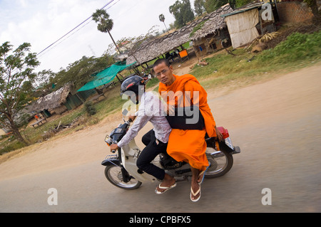 Horizontale Porträt eines buddhistischen Mönchs Reiten als Sozius an Bord ein Moped fahren entlang einer Straße in Kambodscha. Stockfoto