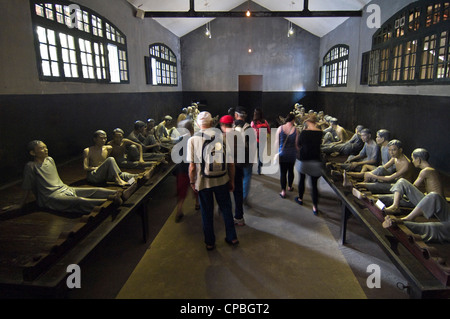 Horizontale Ansicht der Touristen innerhalb eines alten Zelle bei Hoa Lo Prison Museum aka Hanoi Hilton, mit einer Darstellung von Gefangenen in Fesseln, in Hanoi, Vietnam Stockfoto