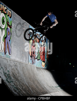 BMX rider führt Tricks bei einem indoor Skatepark. Stockfoto