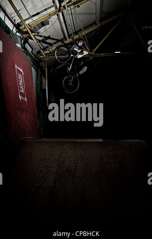 BMX rider führt Tricks bei einem indoor Skatepark. Stockfoto