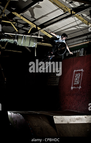 BMX rider führt Tricks bei einem indoor Skatepark. Stockfoto