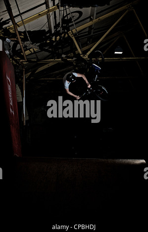 BMX rider führt Tricks bei einem indoor Skatepark. Stockfoto