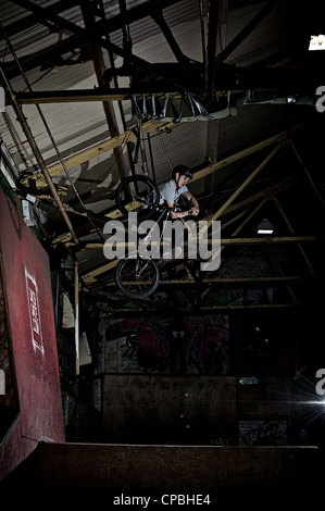 BMX rider führt Tricks bei einem indoor Skatepark. Stockfoto