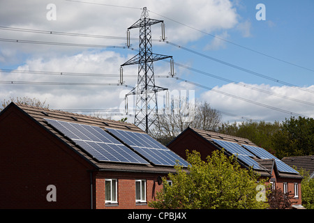Solar-Panels auf Häuser mit Strommasten hinter, Wales, UK Stockfoto
