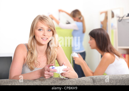 Zwei Freundinnen spielen von Videospielen mit anderen Freund im Hintergrund Stockfoto