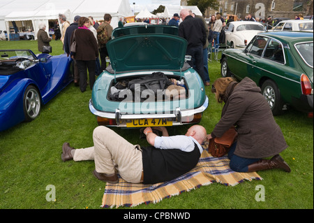 Mann arbeitet unter Heck des E-Type-Jaguar auf der Märsche Transport Festival Ausstellung der Oldtimer und klassische Autos auf Ludlow Food Frühlingsfest Stockfoto