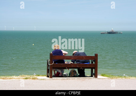 Älteres Ehepaar mit einem Picknick auf einer Bank mit Blick auf den alten Pier in Herne Bay Kent England UK Stockfoto