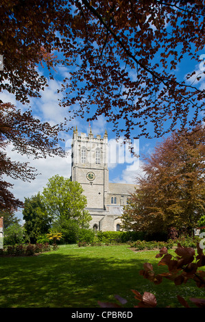 PortraitThe Klosterkirche in Christchurch Dorset UK. Diese Ansicht ist in Priory House Gardens und umrahmt von Bäumen. Stockfoto