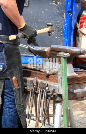 Ein Hufschmied macht ein Hufeisen schlagen mit einem Hammer auf dem Amboss Stockfoto