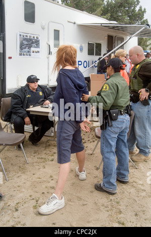 Sheriffs Abgeordneten verhaften eine Obdachlose Frau auf eine herausragende Haftbefehl in Victorville, Kalifornien, während der Suche nach ein Lager. Stockfoto