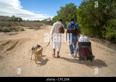 Obdachlose afroamerikanischen paar tragen Spenden in einem Handwagen als sie Kopf für Lager in der Wüste. Stockfoto