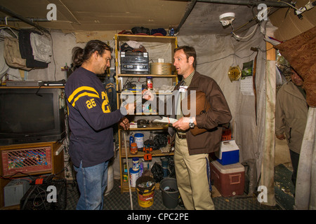 Ein lokaler Minister besucht eine mittellose militärischen Veteran in einem behelfsmäßigen Schutzraum unter Obdachlosen Bewohner von einem primitiven Lager. Stockfoto