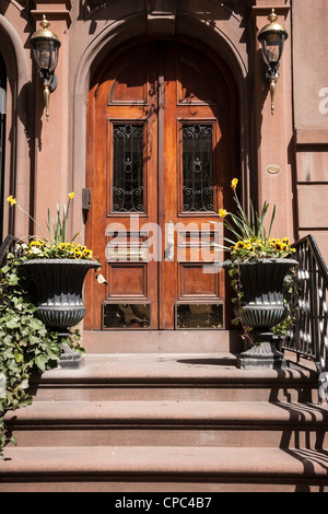 Reich verzierte Sandsteinhaus Eingang mit geschnitzten Holztür und Stein Pflanzgefäße, NYC Stockfoto