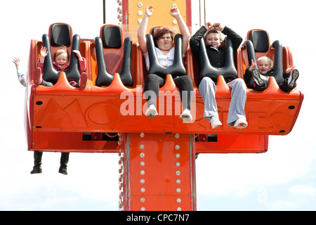 Kinder reiten auf einem Vergnügungspark-Stuhl, der steigt und sinkt, wodurch sie zu schreien und lachen Stockfoto