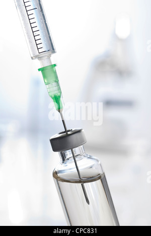 Spritze und Fläschchen von injizierbaren in der Nahaufnahme. Im Hintergrund sehen Sie ein Mikroskop. Stockfoto