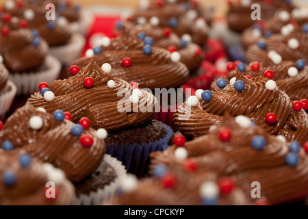 Schokolade verrohrt Vereisung mit Zucker Kugeln auf kleine Kuchen Stockfoto
