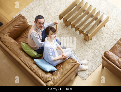 Älteres Paar auf einem Sofa sitzt und das Nachschlagen Stockfoto