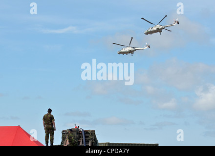 Britische Soldaten sehen wie zwei Royal Navy Black Cats Lynx Hubschrauber Kunstflug durchführen und Mitte Stunts am 23. Juli 2011. Stockfoto