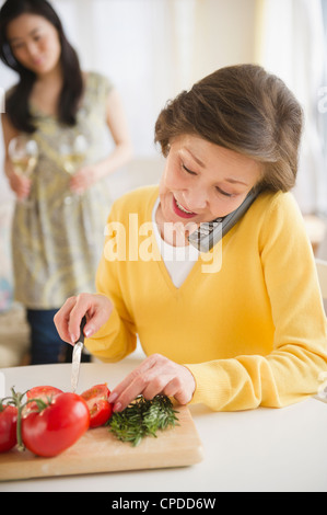 Japanische Frau Schneiden von Gemüse und am Telefon sprechen Stockfoto