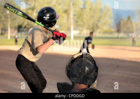 Kleine Liga Baseball Teamplayer junge schlägt Ball und läuft zum ersten Base. Zwei Teams in Uniform. Kleine ländliche Landwirte. Stockfoto