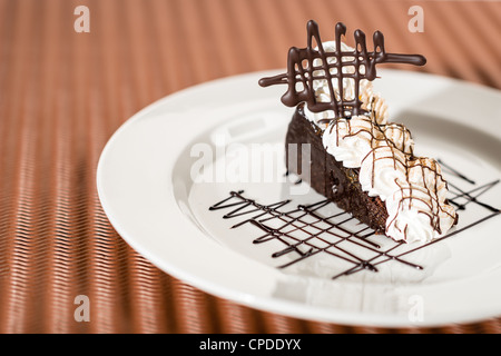 Sachertorte mit Schlagobers auf Schokolade Hintergrund Stockfoto