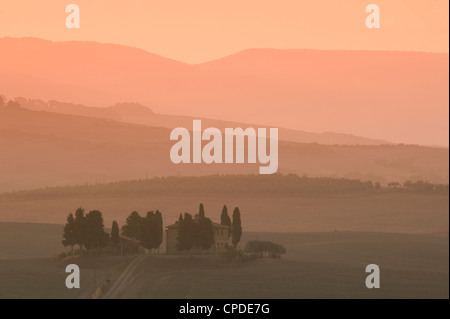 Morgendämmerung am Penella, ein Bauernhaus, umgeben von Zypressen und den nebligen Hügeln des Val d ' Orcia in der Nähe von Pienza, Toskana, Italien, Europa Stockfoto