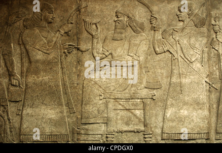 König Ashurnasirpal II sitzt auf seinem Thron zwischen zwei Assistenten. 865-860 V. CHR.. Aus Nimrud. Nordwest-Palast. Stockfoto