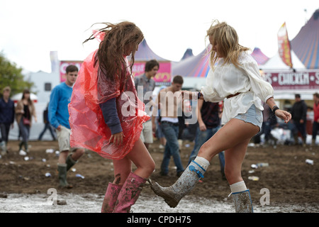 Zwei Mädchen springen und spielen im Schlamm auf einem Musikfestival Stockfoto