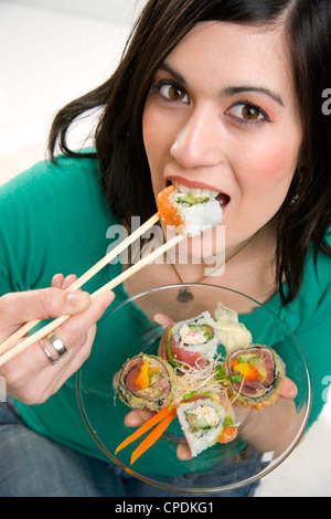 Eine 29 Jahre alte Frau nimmt einen Bissen von einem Sushi-Rollen Stockfoto