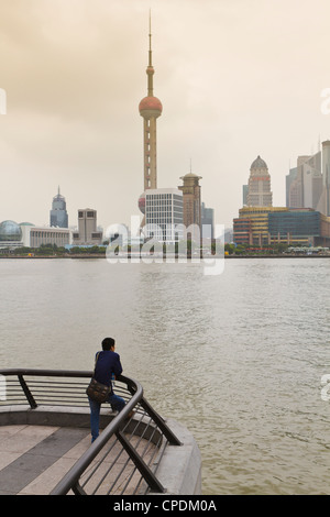 Ein Mann, der Blick auf die Skyline der Oriental Pearl Tower und Pudong über den Huangpu-Fluss vom Bund, Shanghai, China, Asien Stockfoto
