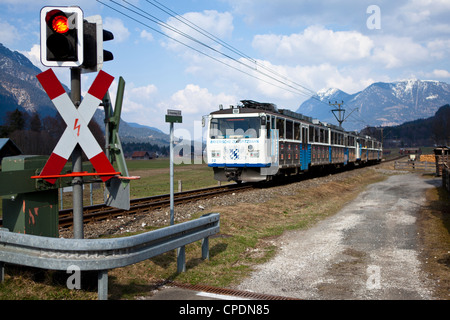 Die Bayerische Zugspitzbahn Zug passiert ein Bahnübergang in Hammersbach auf dem Weg nach Garmisch-Partenkirchen Stockfoto