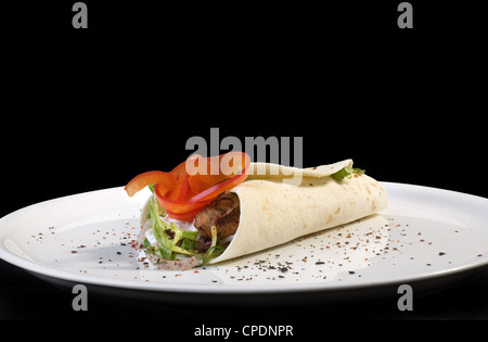 Traditionelle türkische Kebab Tortilla auf Platte auf schwarzem Hintergrund isoliert Stockfoto