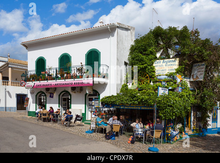 Cafe im Zentrum von der Binnenschifffahrt Dorf Alte mit der Dorfkirche auf der linken Seite, Algarve, Portugal Stockfoto