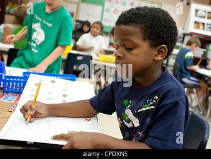 Afrikanisch-amerikanischen männlichen Kindergarten Student arbeitet an seinem Schreibtisch, während des Unterrichts an der Volksschule von Texas Stockfoto