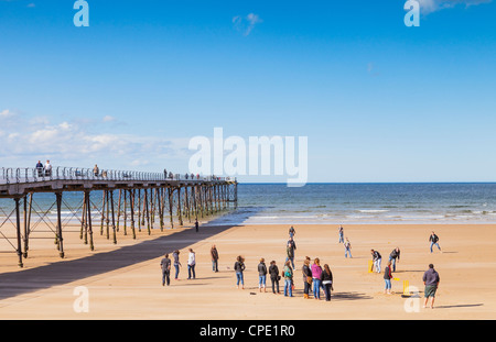 Eine Gruppe von Menschen am Strand von Saltburn-by-the-Sea, Cricket, spielen einige andere beobachten. Stockfoto