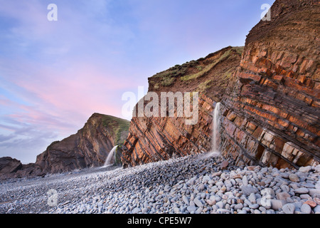 Sandstein Gesteinsschichten und Wasserfälle bei Sandymouth Strand bei Sonnenuntergang, in der Nähe von Bude, Cornwall, England, Vereinigtes Königreich, Europa Stockfoto