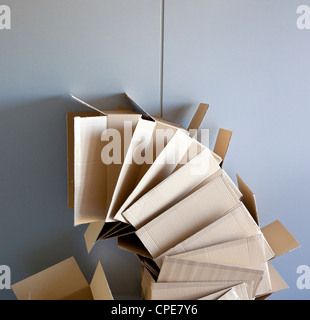 offene Kartons gestapelt auf gekrümmten Kreisform auf graue Wand Stockfoto