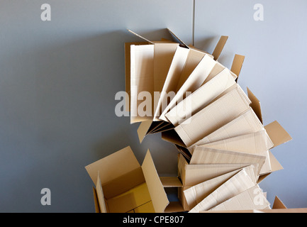 offene Kartons gestapelt auf gekrümmten Kreisform auf graue Wand Stockfoto