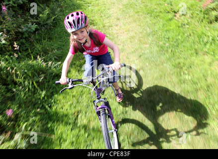 Ein 8 Jahres altes Mädchen genießt eine Radtour durch die Landschaft an einem sonnigen Tag. Stockfoto