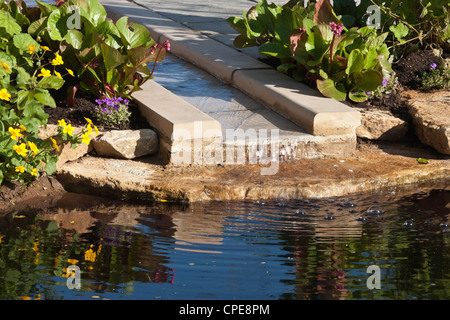 Ein Garten mit Gartenrillwasser aus Steinwasser Randpflanzen, die Großbritannien Pflanzen Stockfoto