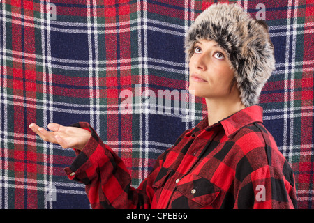 Schöne junge Frau tragen Holzfäller Hemd posiert wie Dummy anzuzeigen. Lustige Studio erschossen vor einem karierten Hintergrund Stockfoto