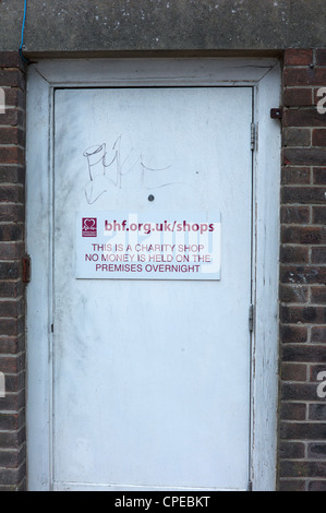 Hintertür ein British Heart Foundation Charity Shop anzeigt, dass kein Geld über Nacht auf dem Gelände gehalten wird Stockfoto