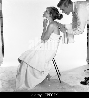 Werbung nach wie vor von sechziger Jahre zeigen junge Dame sitzt auf einem Stuhl in einem Studio mit Haut-Creme auf dem Rücken von einem männlichen setzen. Stockfoto