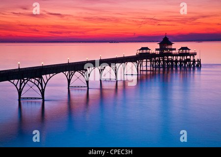 Die Sonne geht über den Bristolkanal hinter dem Pier in Clevedon, Somerset, England, UK Stockfoto