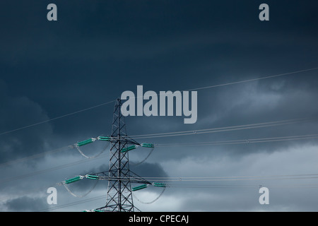 Strommasten und Power Kabel gegen dunklen Gewitterhimmel, England Stockfoto