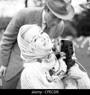 Bild aus den 1960er Jahren zeigen ein paar außen, mit der Dame trägt einen Schal um ihr Gesicht, einen kleinen Hund umarmt. Stockfoto