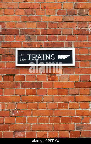 Um die Züge auf einer roten Backsteinmauer Sign. Staverton, Devon, England Stockfoto